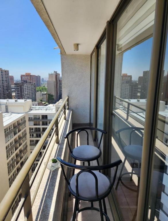 two chairs on a balcony with a view of a city at Céntrico y lindo departamento in Santiago