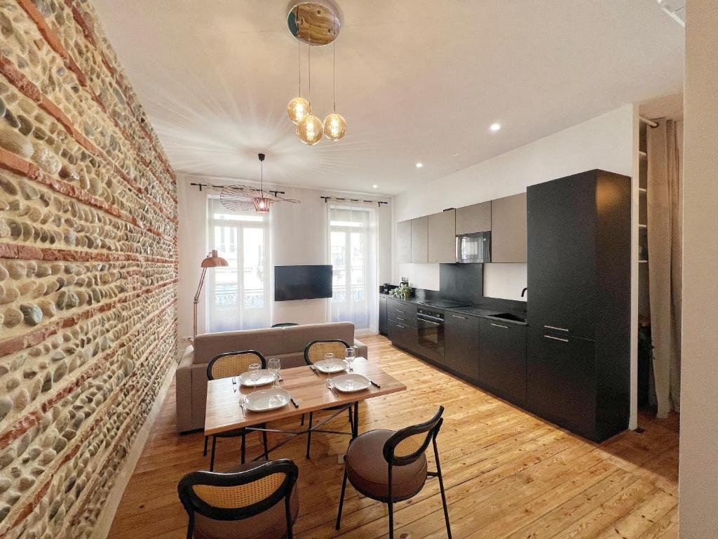 une cuisine et une salle à manger avec un mur en briques dans l'établissement L'Enlumineur - Centre - Luxe - Balcon - Climatisation, à Toulouse