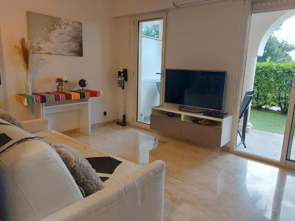 un salon avec un canapé et une télévision à écran plat dans l'établissement Bagatelle Studio 3étoiles rez de jardin Axelle LocAppart, à Mandelieu-la-Napoule