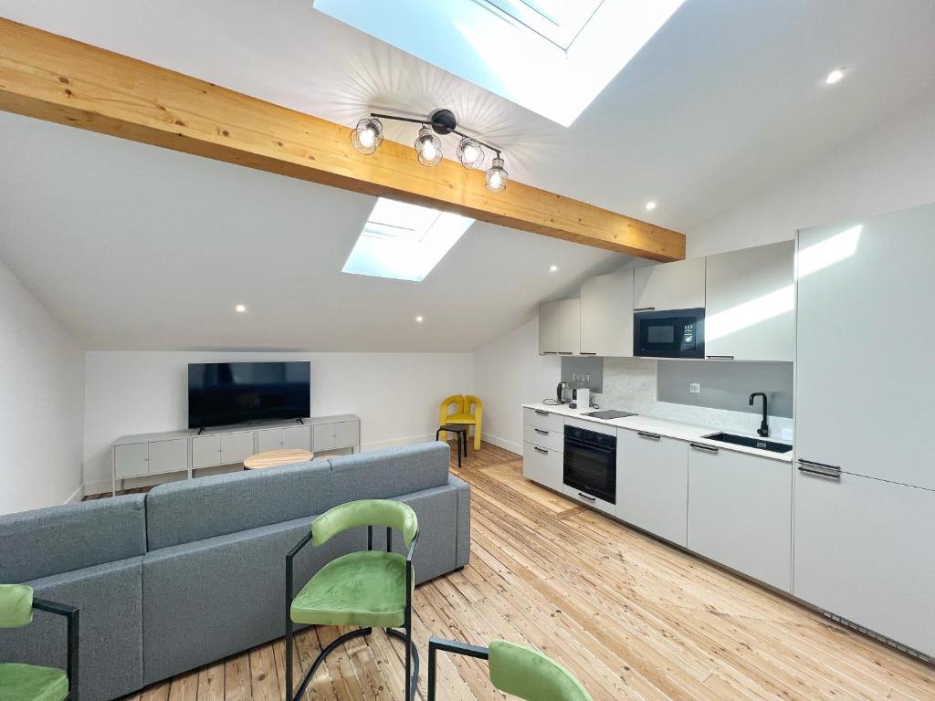 Il dispose d'une cuisine ouverte et d'un salon avec un canapé gris. dans l'établissement Le Tapissier - Centre - Luxe - Climatisation, à Toulouse