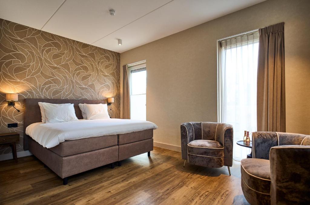 een hotelkamer met een bed en een stoel bij Eilandhotel Texel - Nieuw geopend hotel in De Cocksdorp