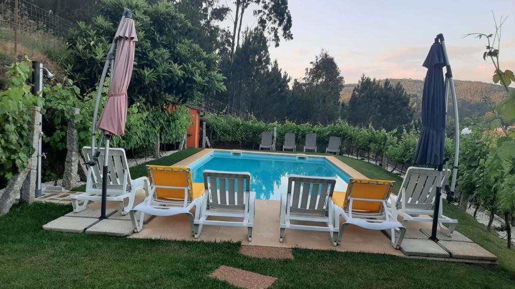 a group of chairs and umbrellas next to a pool at Casa da Tia Bina in Castelo de Paiva