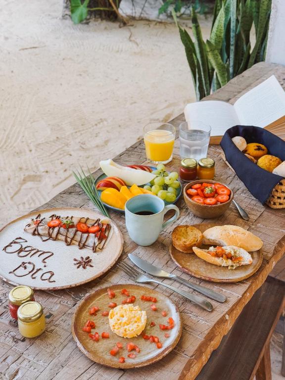 a wooden table with plates of food on it at Villa Mango Jeri in Jericoacoara