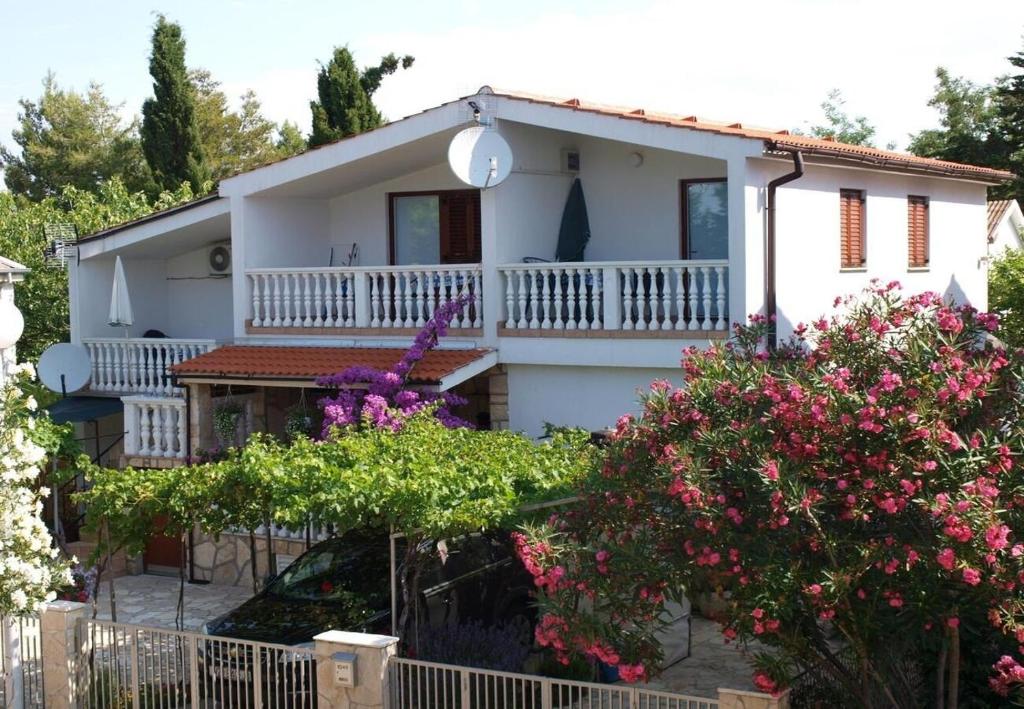 a white house with flowers in front of it at Apartment Dobri in Batalaži