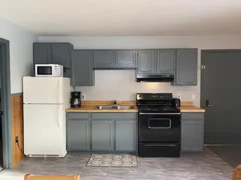 a kitchen with a black stove and a white refrigerator at Cozy Mountain View Condo at Powderhorn Mountain in Bessemer