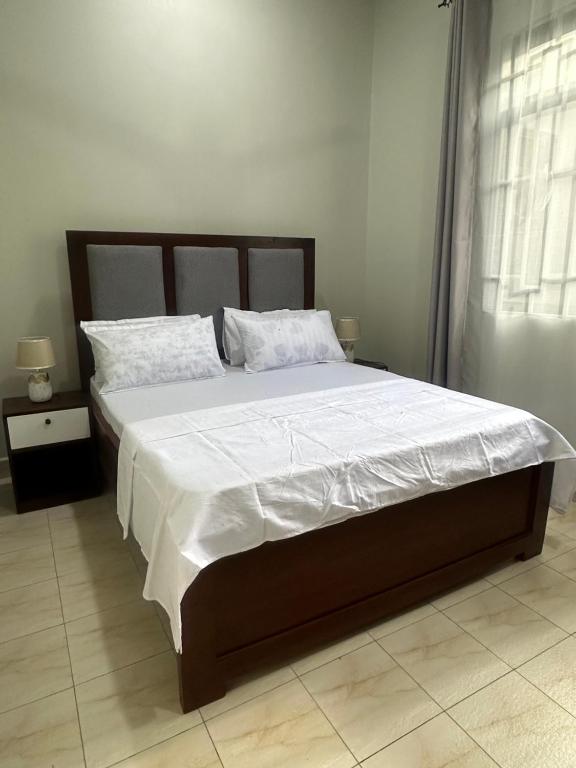 una camera da letto con un letto grande con lenzuola e cuscini bianchi di Blue wave loft a Dar es Salaam