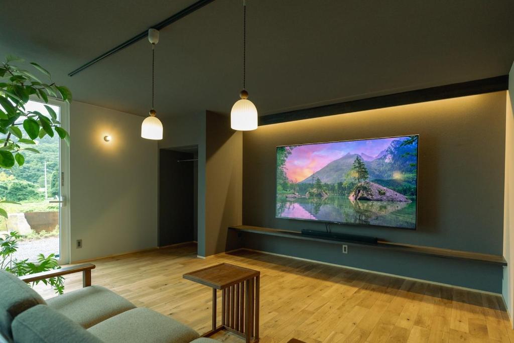 Una sala de estar con un televisor de pantalla plana en una pared. en MARUMORI-STAY fudo, en Ōuchi