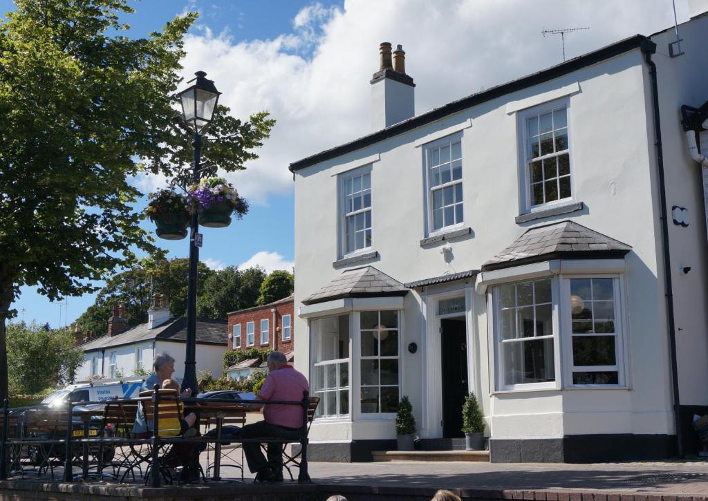 dos personas sentadas en una mesa frente a un edificio blanco en No. 23 at The Moorings, Chester, en Chester