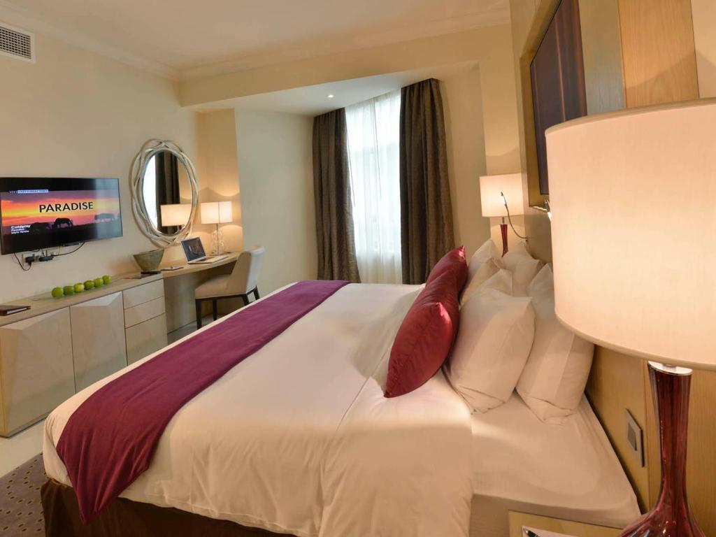 Habitación de hotel con cama con almohadas rojas en Gulf Executive Residence en Manama