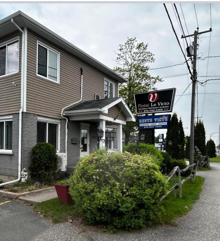 a house with a sign in front of it at Motel Le Victo in Victoriaville