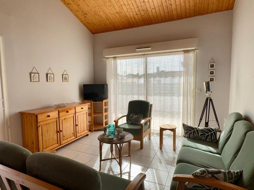 un salon avec un canapé, des chaises et une télévision dans l'établissement Maison spacieuse à 300m de la plage avec terrasse, pour 6 pers., Saint-Hilaire-de-Riez - FR-1-323-378, à Saint-Hilaire-de-Riez