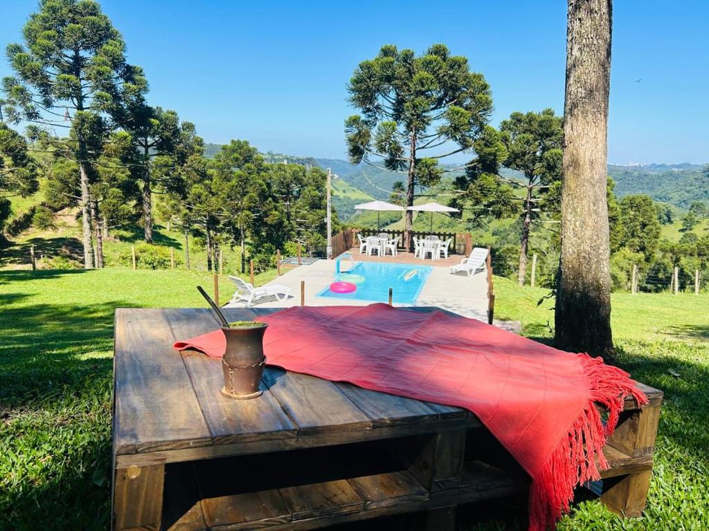 un tavolo in legno con coperta rossa accanto alla piscina di Villa's Serra - Casa aconchegante em meio a natureza a Caxias do Sul