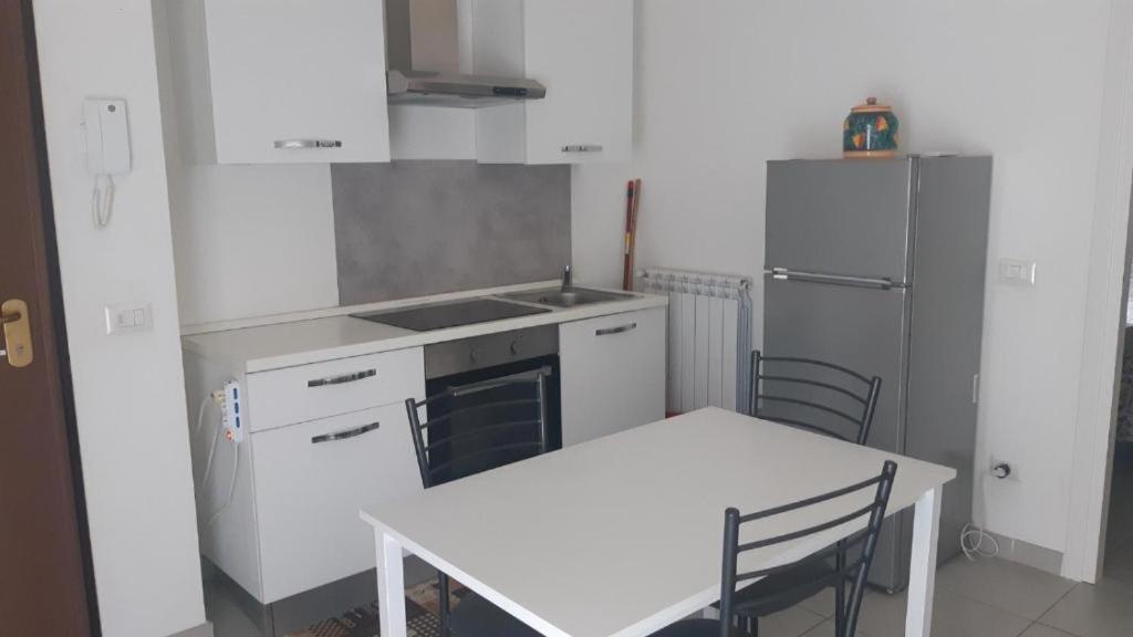 a white kitchen with a table and a refrigerator at ATOS - Camera con Bagno e Cucina privati in Randazzo