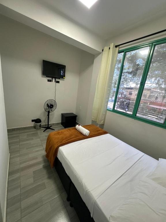 a bedroom with a bed and a tv and a window at HOTEL PUERTO DULCE - La Virginia in La Virginia