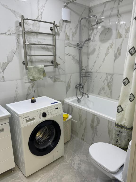 a washing machine in a bathroom with a toilet and a tub at Duplex in Baganashyl