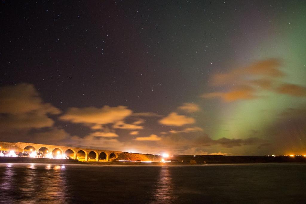 un puente sobre el agua por la noche con luces verdes en Grant Arms Hotel en Cullen