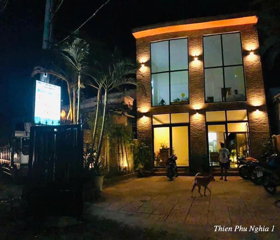 a man walking a dog in front of a building at night at Thien Phu Nghia 1 - Homestay Phu Quoc in Phu Quoc