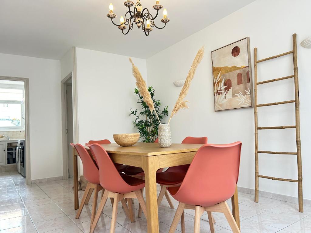 une salle à manger avec une table en bois et des chaises roses dans l'établissement Dahlias- 6 pers Vrai tout à pied, à Saint-Raphaël