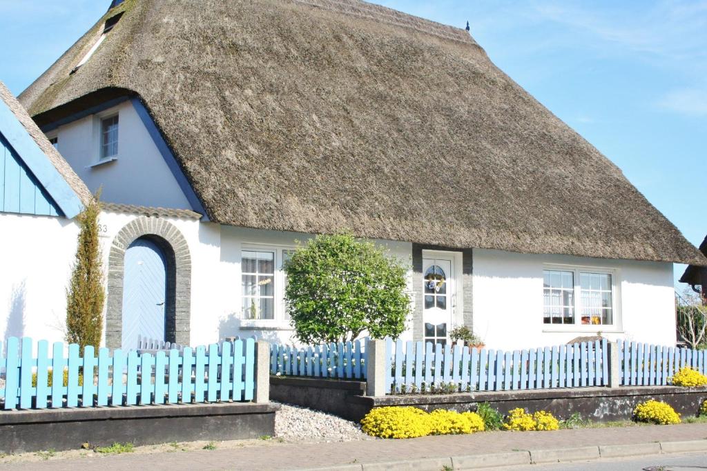 a white house with a thatched roof and a white picket fence at Komfortferienwohnung Anker & Steuerrad in Putbus