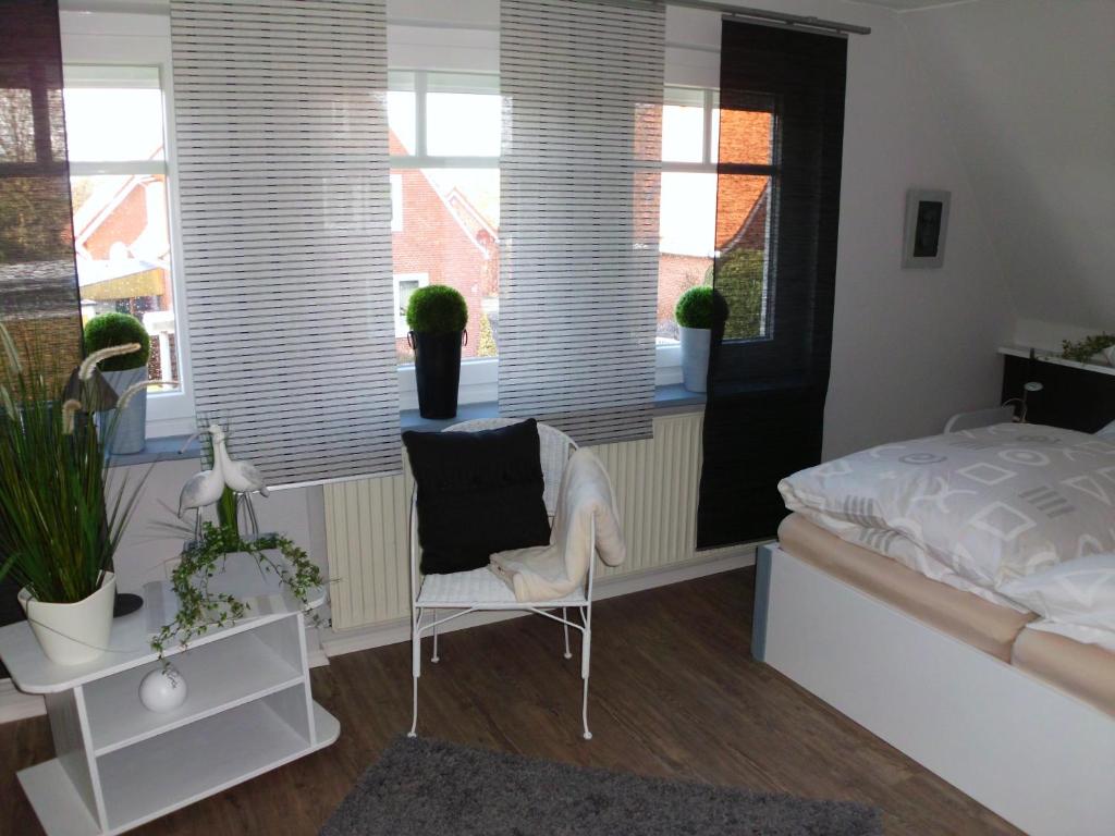 een slaapkamer met een bed, een stoel en ramen bij Ferienwohnung Emma in Leer