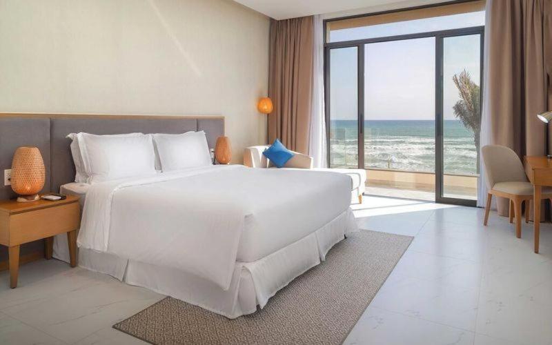 a bedroom with a large white bed with a view of the ocean at Serene Villa trong Wyndham Garden Cam Ranh Resort in Cam Ranh International Airport