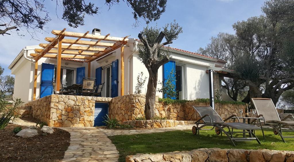 a house with a stone wall and chairs in the yard at Beach house Adriana in Lun