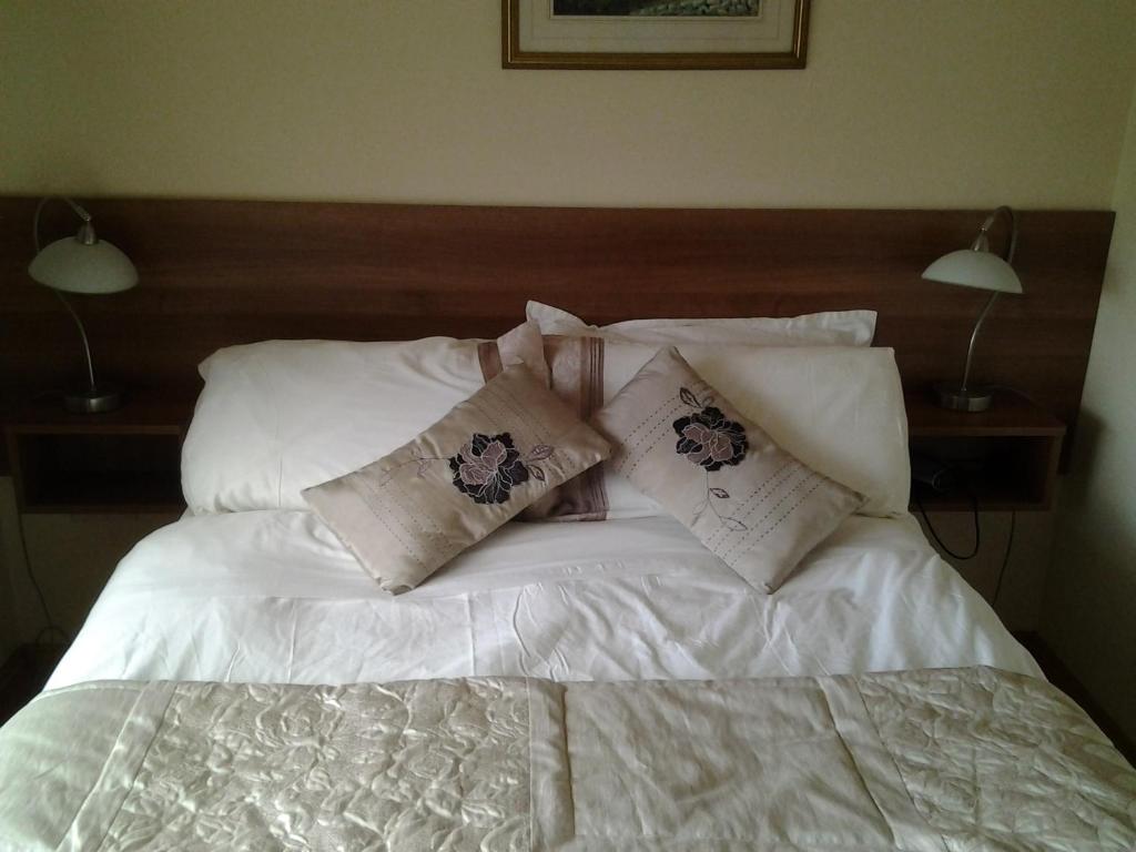 een bed met witte lakens en kussens erop bij Gardenfield House Bed & Breakfast H91vh02 in Galway