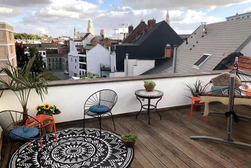 d'un balcon avec deux chaises et une table sur le toit. dans l'établissement Cozy & Spacious Duplex with an Amazing Terrace, à Anvers
