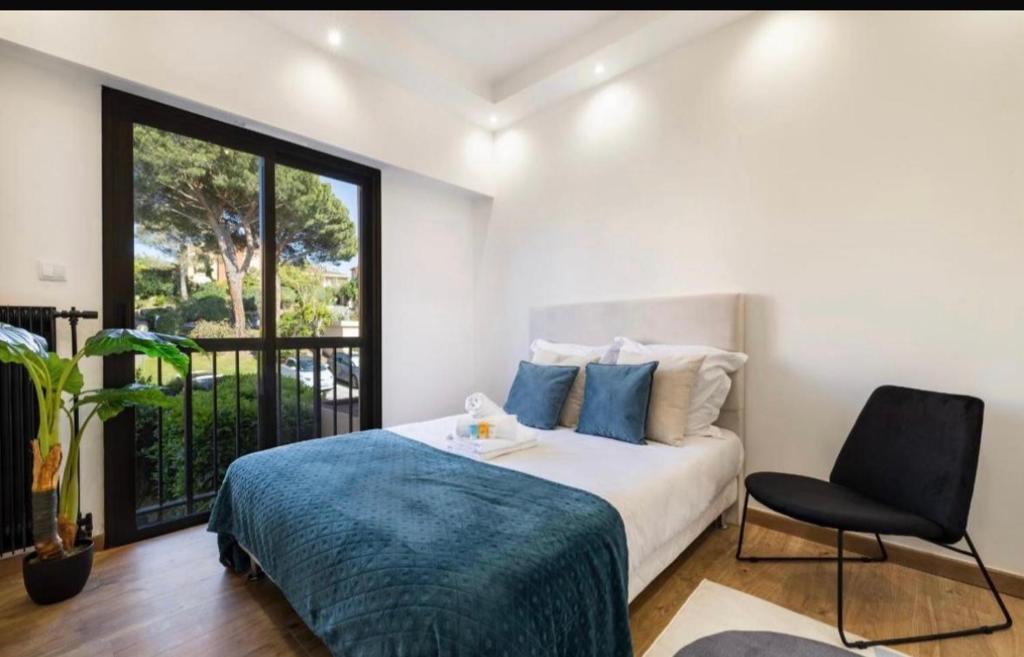 une chambre avec un lit, une chaise et une fenêtre dans l'établissement Appartement haut standing - Luxury apartment - Cannes- Croisette- Centre ville- Vue Tennis -Vue Piscine -Parking privé - Terrasse- Plage, à Cannes