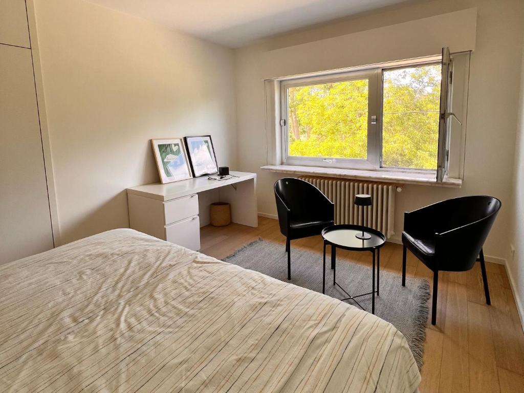 een slaapkamer met een bed, een bureau en stoelen bij B&B near Ghent in Merelbeke