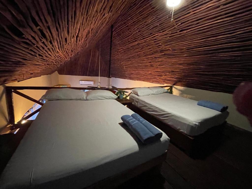 two twin beds in a room with a wood wall at Treehouse Loft in Prime Location in Playa del Carmen