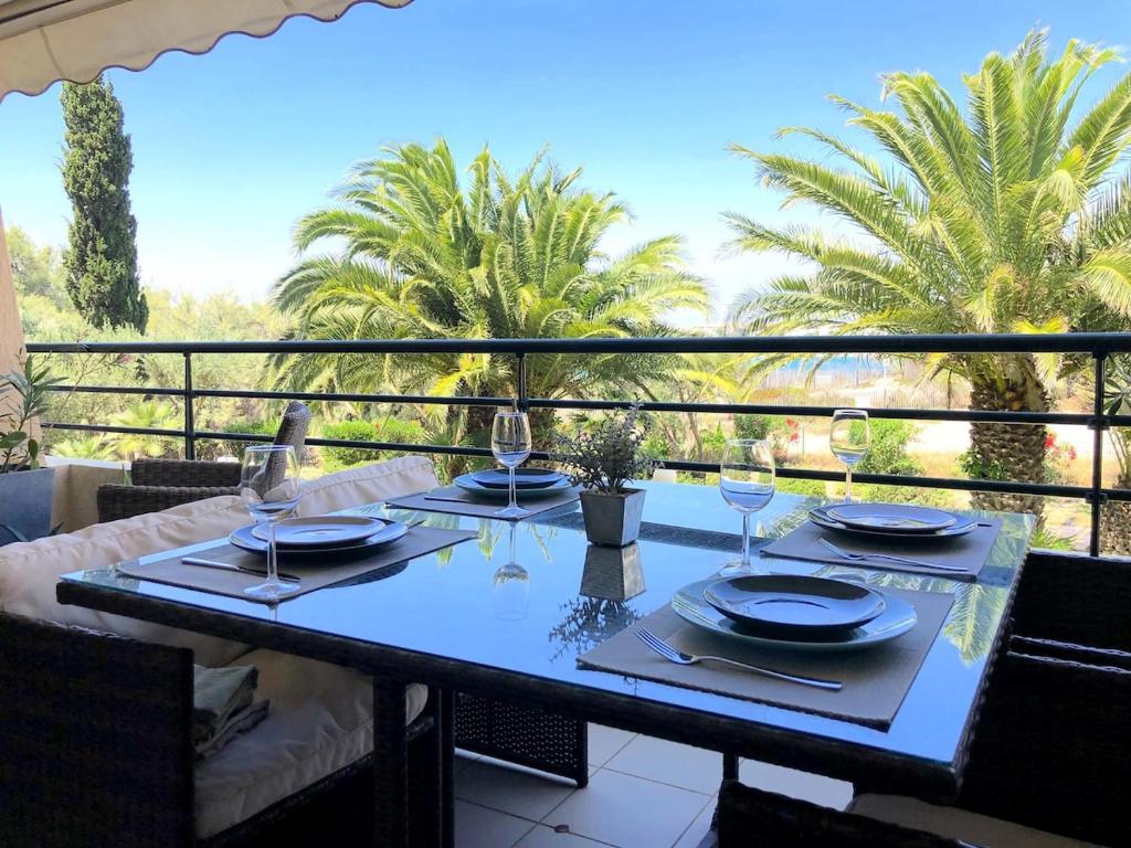une table avec des assiettes et des verres à vin sur un balcon dans l'établissement Les pieds dans l'eau T2 cabine avec vue mer et Piscine, à Sète
