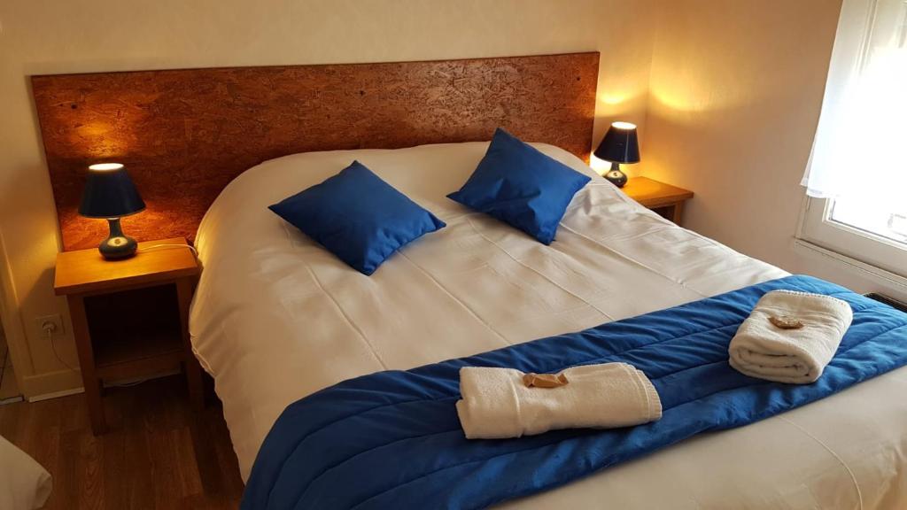 1 cama grande con almohadas azules y toallas. en Le Petit HERMITAGE - Gite 4 pers, en Massiac