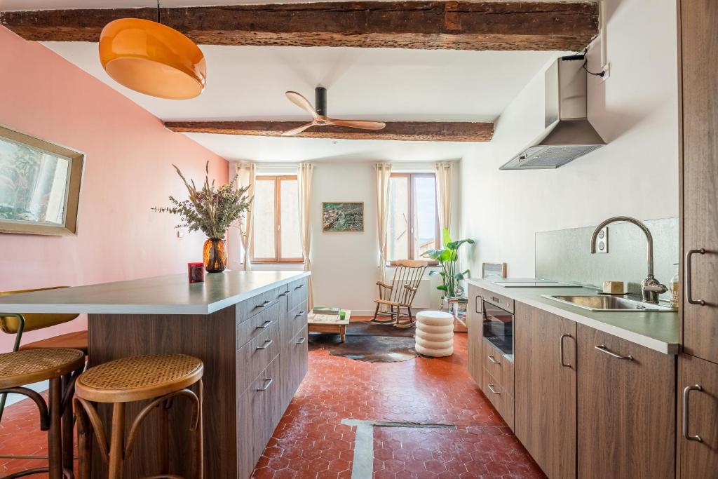 une cuisine avec des murs roses et des placards en bois dans l'établissement Superbe appartement au cœur du Panier - Vieux-Port, à Marseille