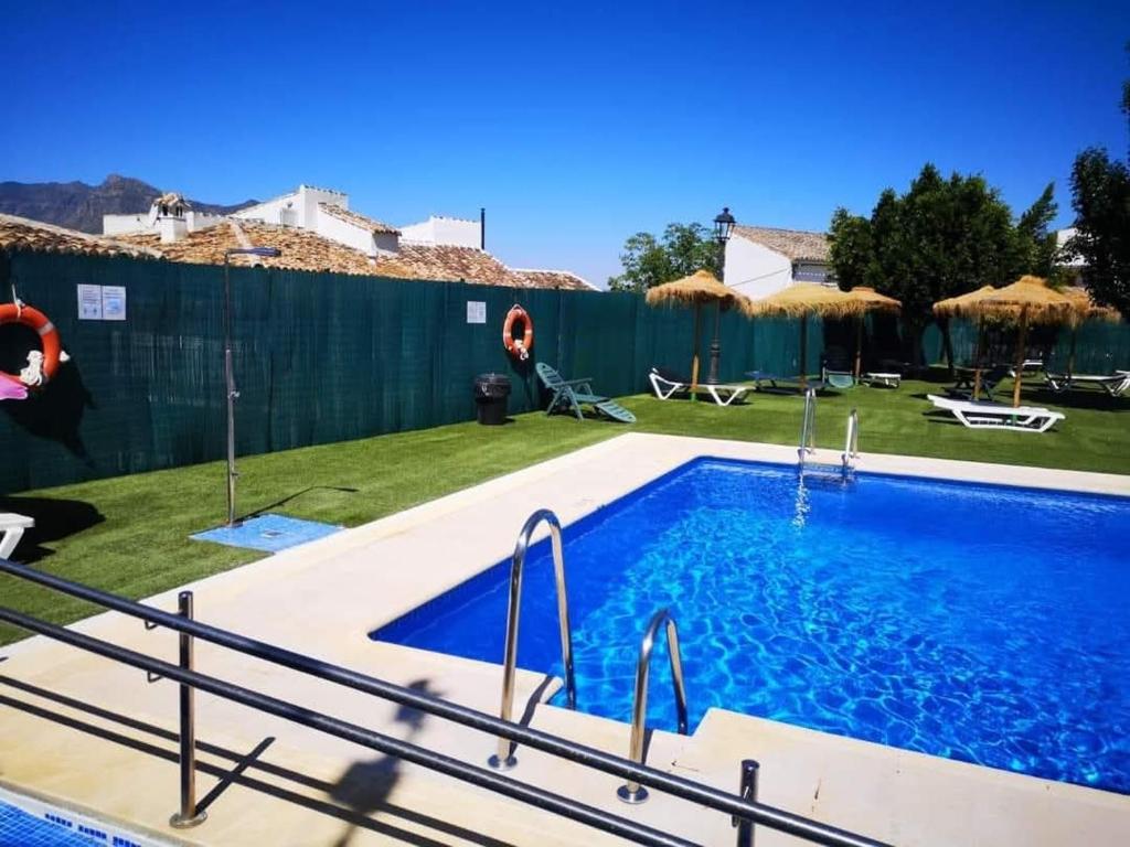 een zwembad in een tuin met een hek bij Casa del Tío Paco in Montecorto