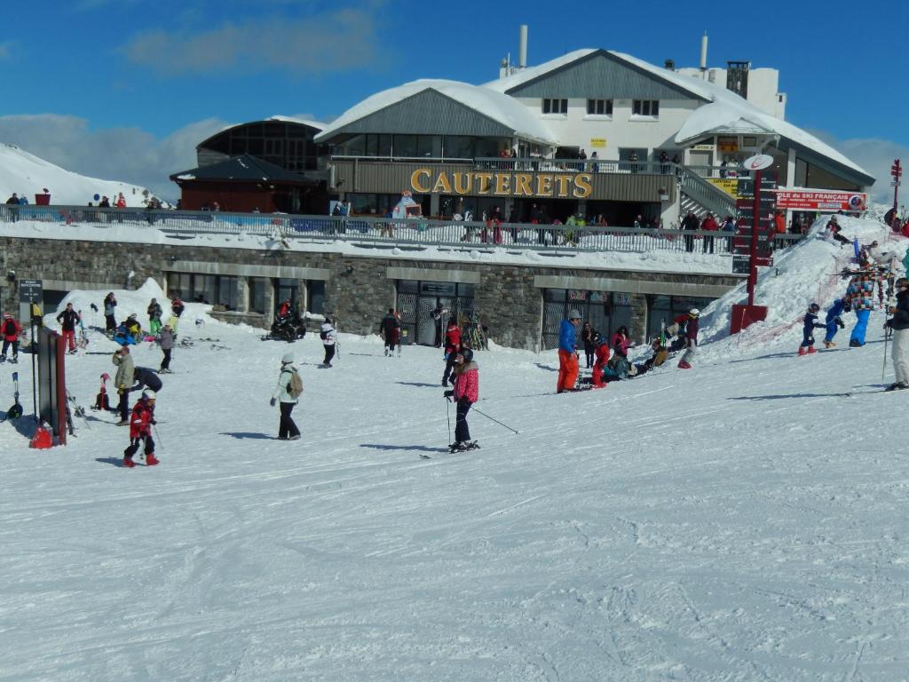 a group of people skiing in the snow in front of a ski lodge at Les Estives de Cauterêts in Cauterets