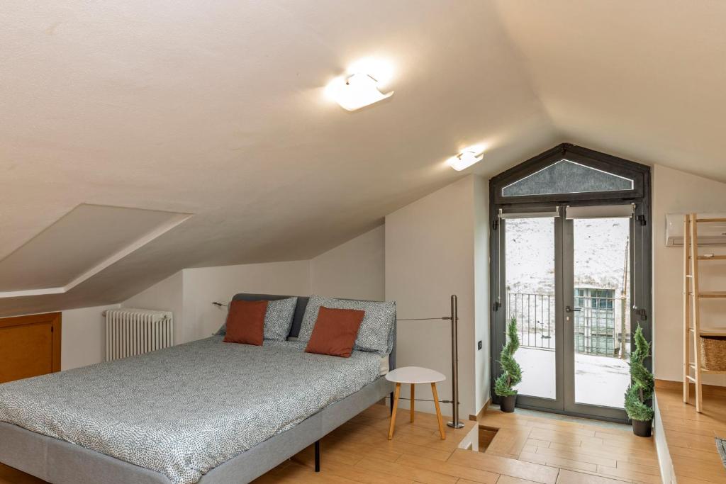 a bedroom with a bed and a large window at Appartamento Palazzo dei Duchi in Avigliana