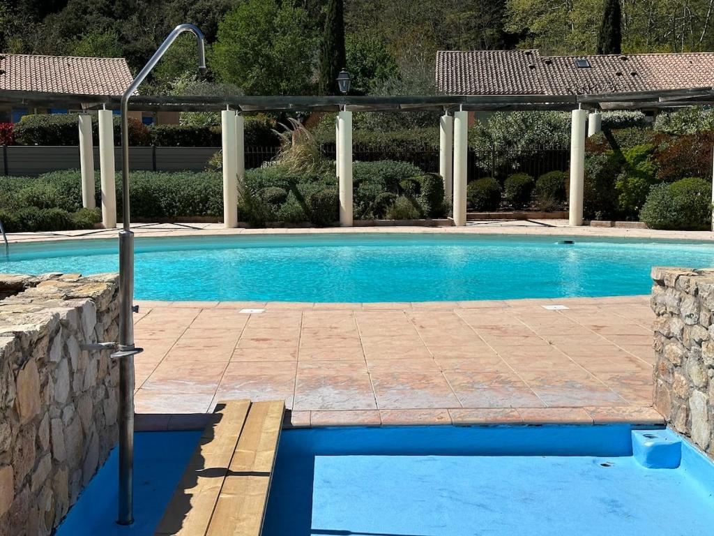 a swimming pool with a stone wall and a blue pool at Compact vacation house in Vidauban in Vidauban