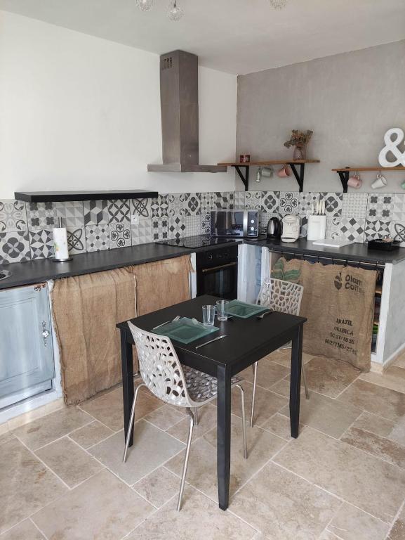 une cuisine avec une table et des chaises noires dans l'établissement Appartement T2 en campagne, à Sarrians