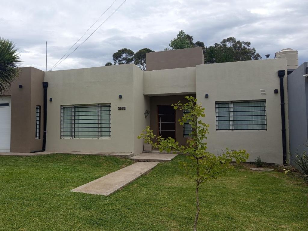 una casa blanca con un árbol delante en La Casa de Vero en Acantilados, en Mar del Plata