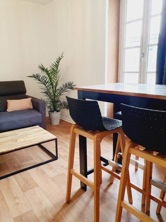 un salon avec une table, des chaises et un canapé dans l'établissement Appartement - La Rochelle, à La Rochelle