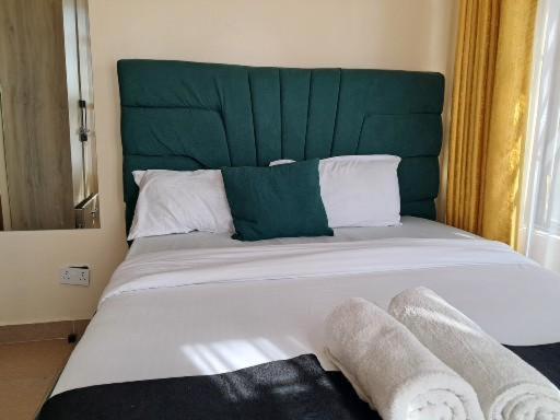 a bedroom with a large bed with a green headboard at Nash issah - 2BEDROOM Excutive Air in Nakuru