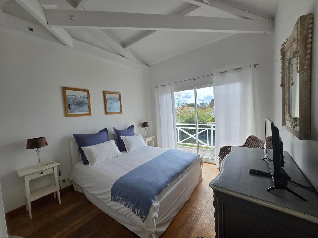 a bedroom with a bed and a tv and a window at La Maison Blanche in Andernos-les-Bains