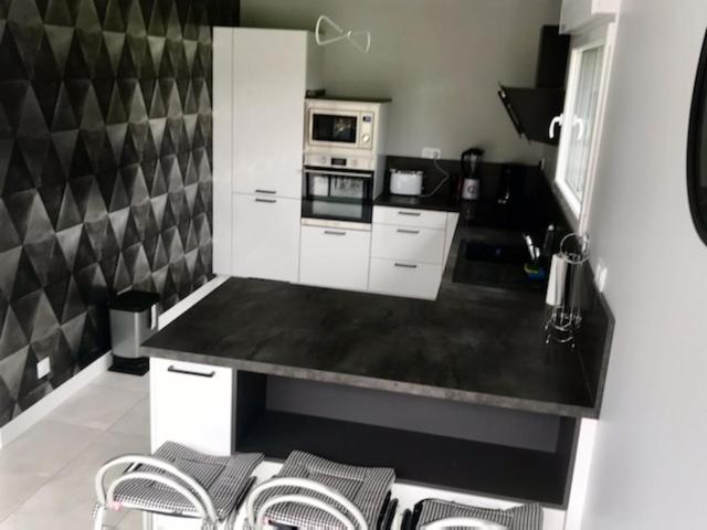 une cuisine avec des armoires blanches et un comptoir noir dans l'établissement maison entiére, à La Celle-sous-Gouzon