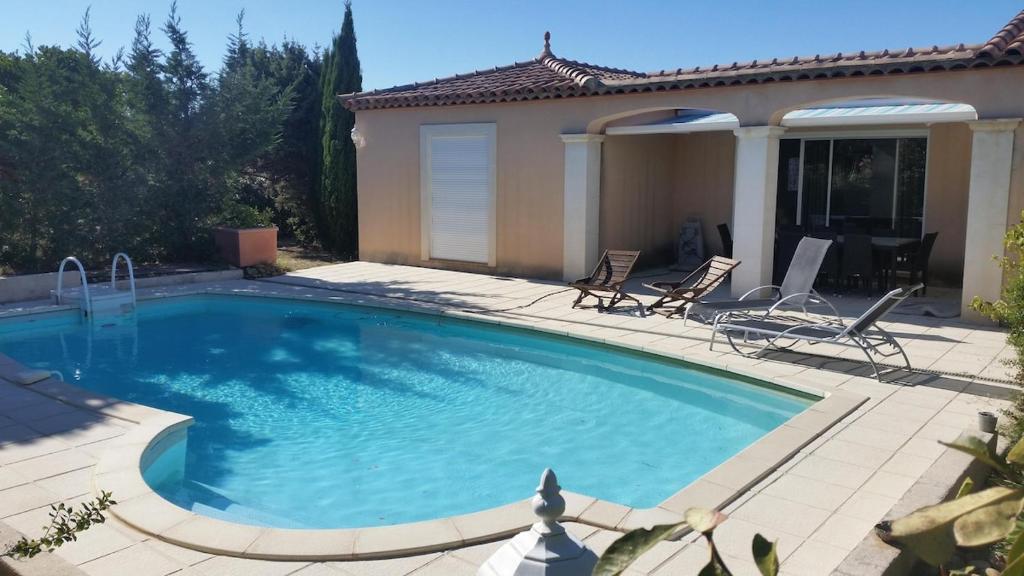 a swimming pool with two chairs and a house at VILLA AVEC PISCINE au calme ! in Rochefort-du-Gard