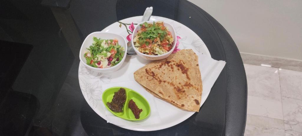 a plate of food with a sandwich and a salad and a salad at Sthanvi Homestey in Ujjain