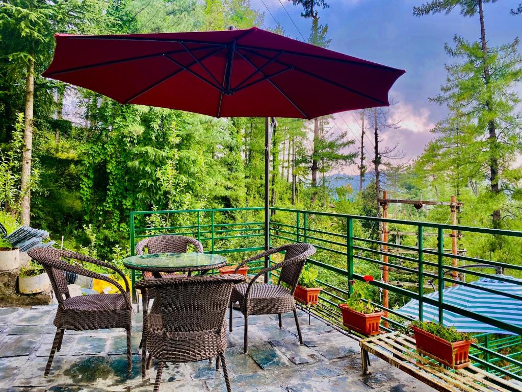 a patio with a table and chairs and an umbrella at Staycation Premium Mashobra - A Nature Valley Retreat Resort in Shimla