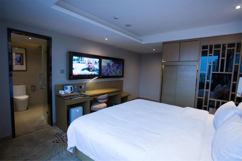 a bedroom with a white bed and a tv on the wall at Lavande Hotel Foshan Shunde Ronggui in Shunde