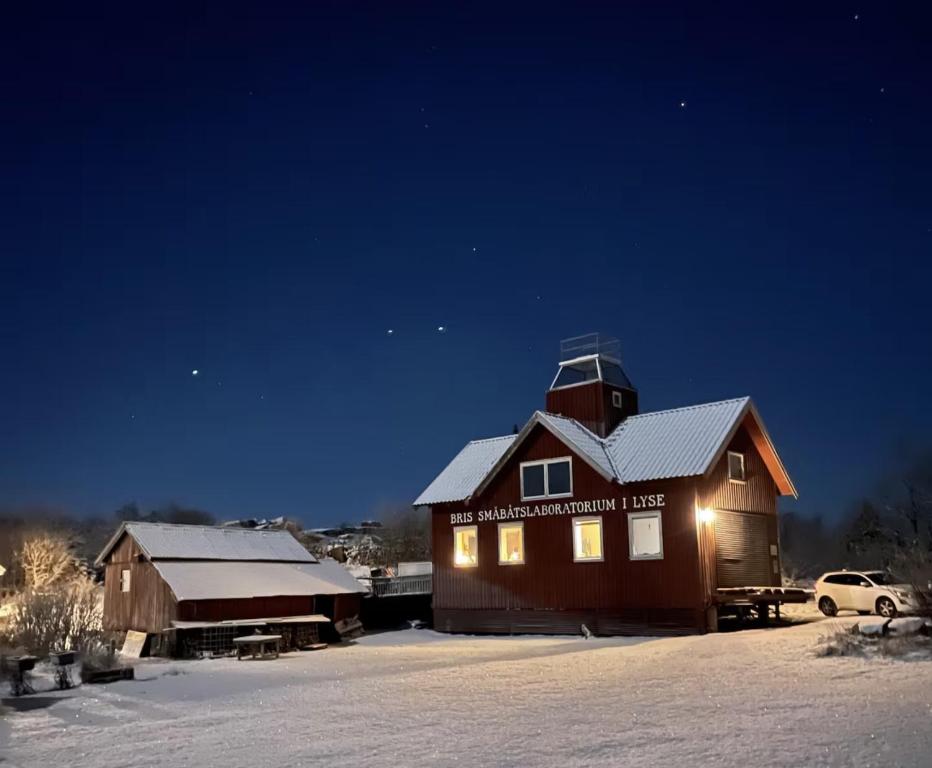 a barn in the snow at night with lights on at Unik villa med utsiktstorn, orangeri och badtunna in Lysekil