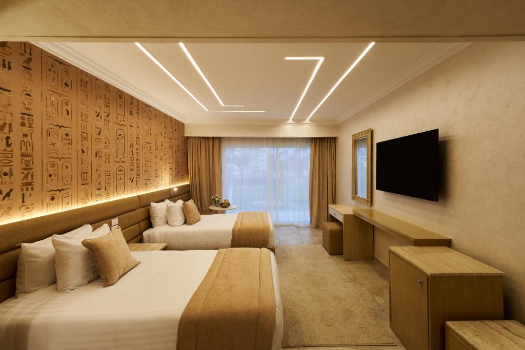 Una habitación de hotel con dos camas y un televisor. en Pyramids Park Resort Cairo, en El Cairo
